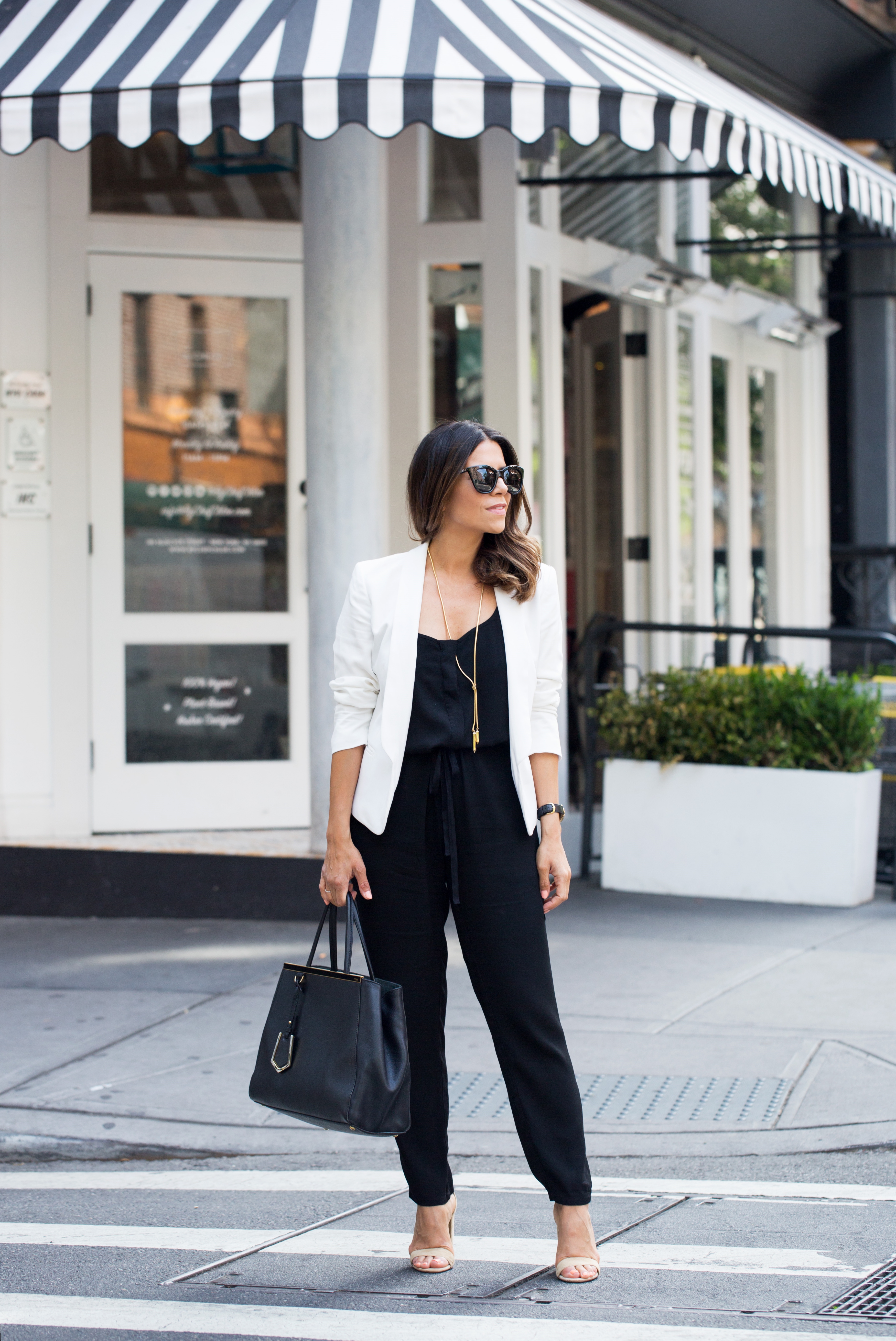 How to wear a black jumpsuit to work with a white blazer and nude sandals in the summer on Corporate Catwalk