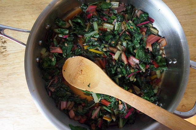 A stainless steel pan full of cooked chard, emerald green with bright flecks of yellow and red. This pan just looks so wholesome. Wholesomely delicious.