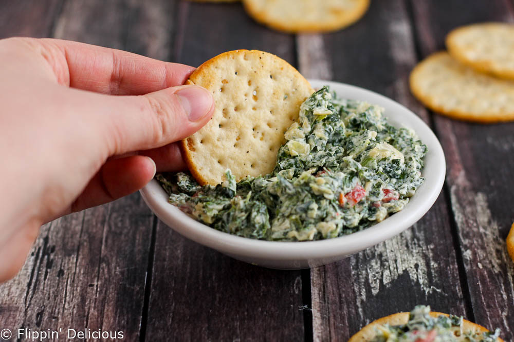 Creamy gluten-free skinny spinach artichoke dip made with greek yogurt. Packed full of veggies and protein, and less guilt when you eat it all.