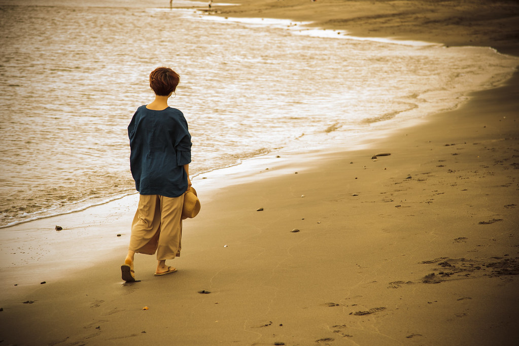 失恋して寂しそうに浜辺を歩く女性