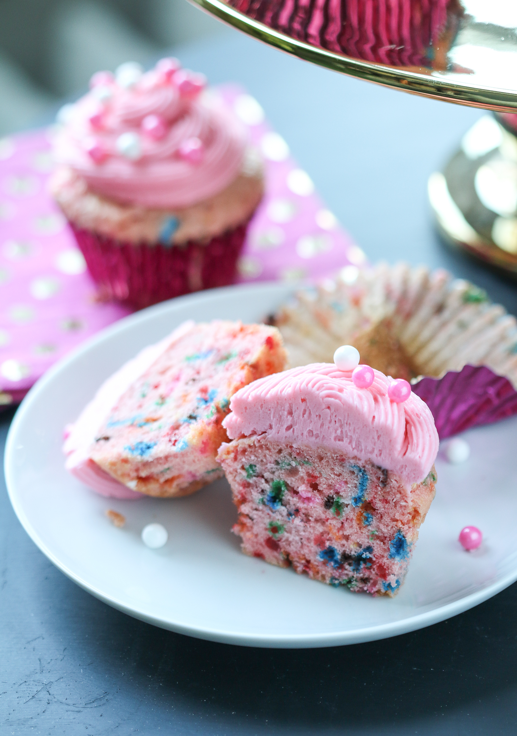 Pink funfetti cupcake cut in half on a white plate